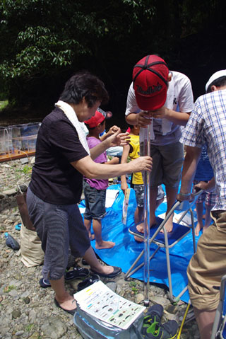 川の水の透視度を調べる子ども